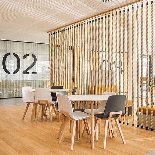 A room with a table chairs and a wall with a curtain.