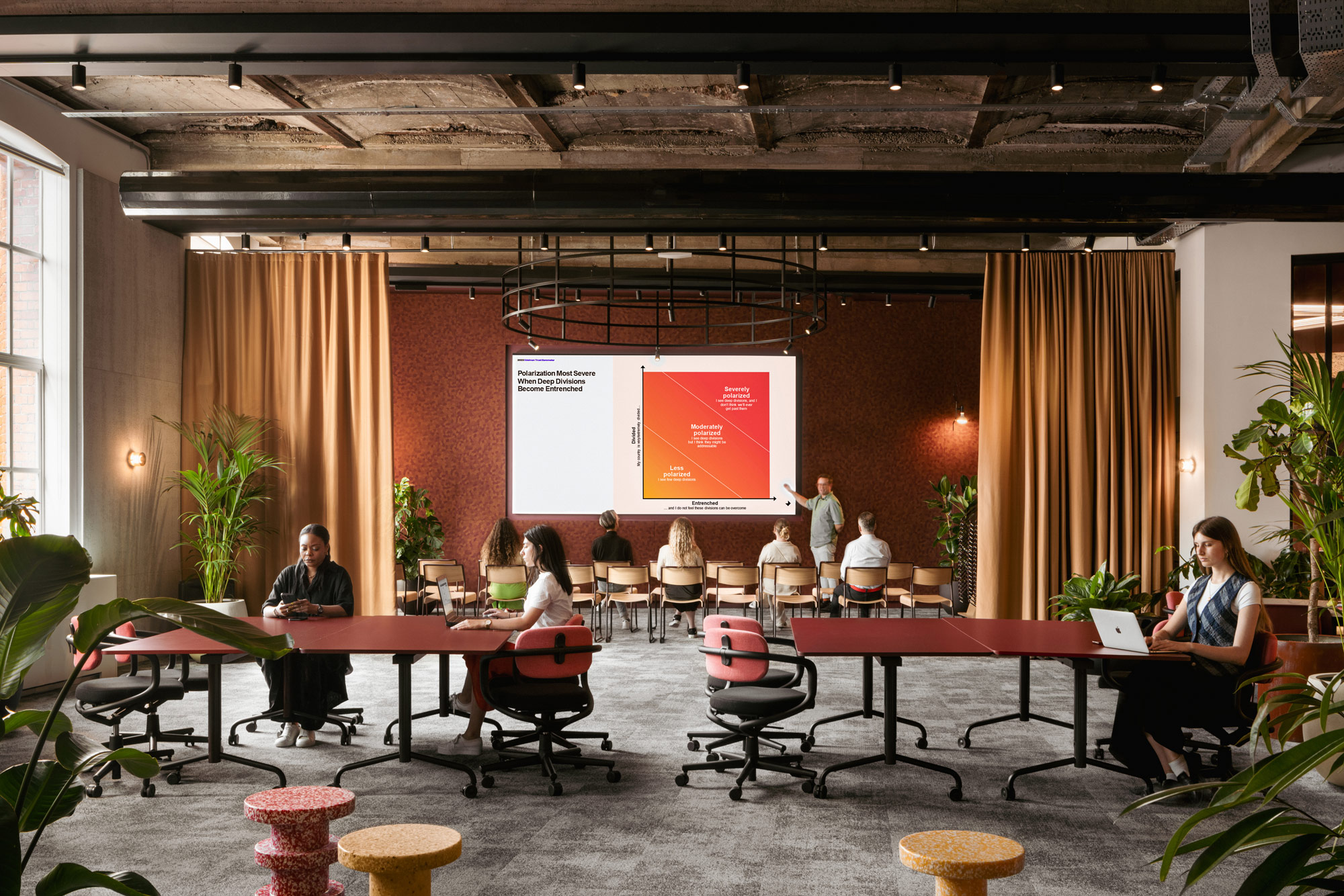 A group of people sitting in chairs in a room with a large screen.