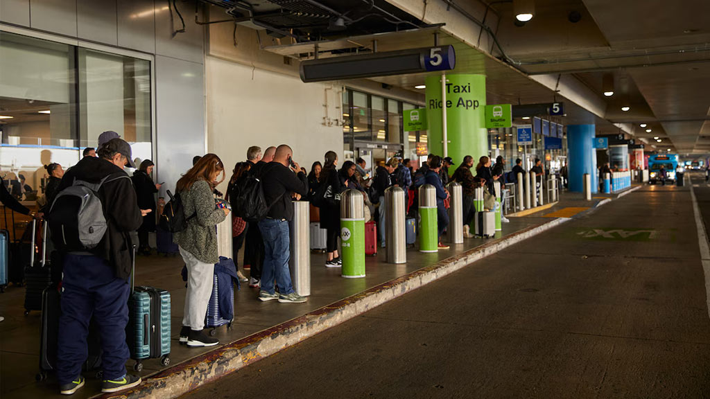 Travelers at LAX wait for the shuttle to a ride-hailing pickup area. (Sean Scheidt for The Washington Post)